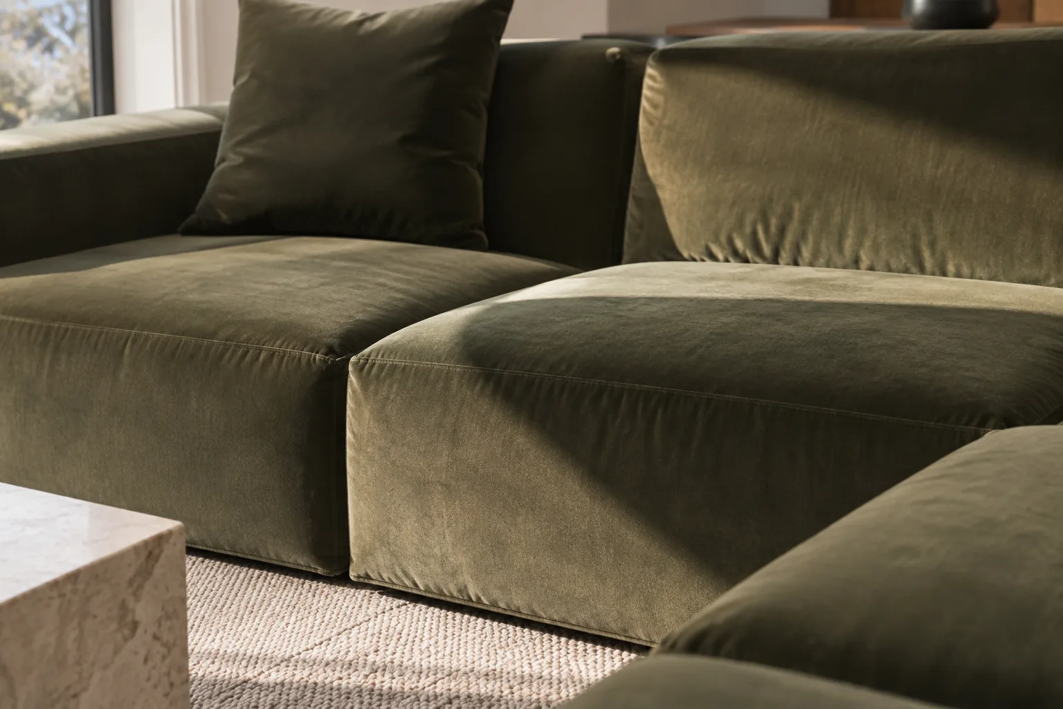 Assise en velours d’un canapé modulable présentant des nuances plus claires et plus foncées sous une lumière latérale.